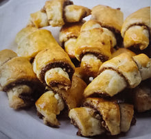 Load image into Gallery viewer, A plate piled with golden-brown, crescent-shaped Cinnamon Walnut Rugelach pastries, each with a buttery, slightly glossy exterior and a rich nutty filling.
