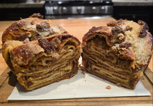 Load image into Gallery viewer, A sliced loaf of swirled, layered Pumpkin Babka with Candied Pecans on a wooden cutting board.
